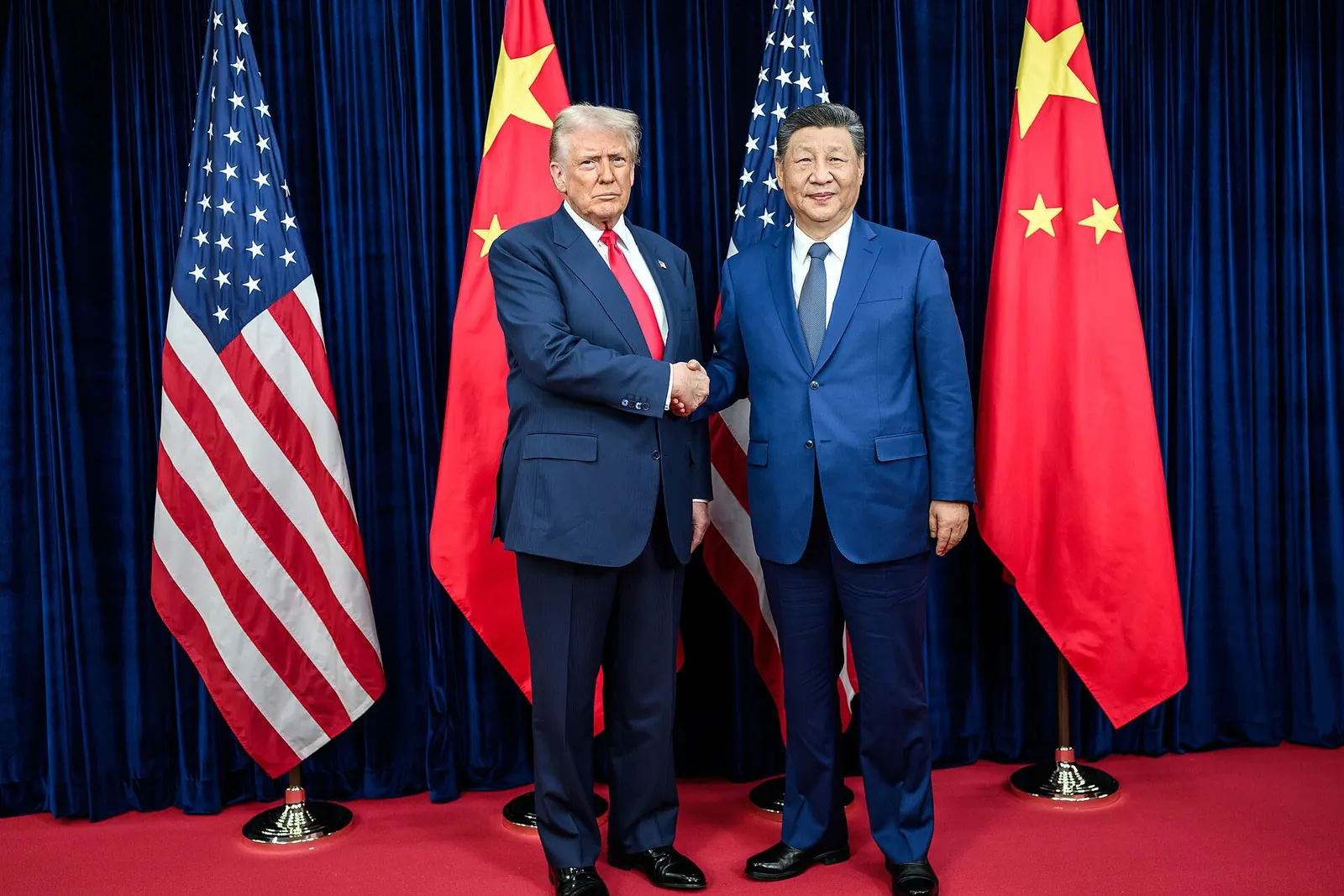 Дональд Трамп и Си Цзиньпин пожимают руки на фоне флагов США и Китая
